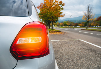 Close Up Tail lamp of The car at car park during the autumn season with copy space and blur forest and Leaves change color background in travel and transportation concept. © boophuket
