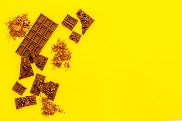 Chocolate frame. Broken bars and cocoa powder on yellow background frame copy space