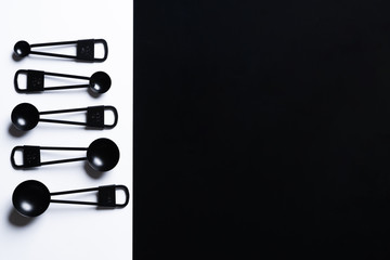 Black measuring spoons on black and white background.
