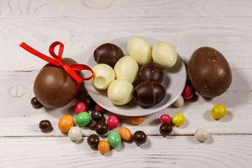 Easter composition with chocolate eggs on white wooden background