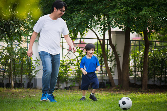 Asian father Father and son playing football in the garden