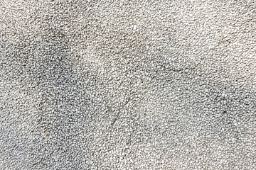 Exposed aggregate concrete in closeup made of small pebbles in different grey color shade