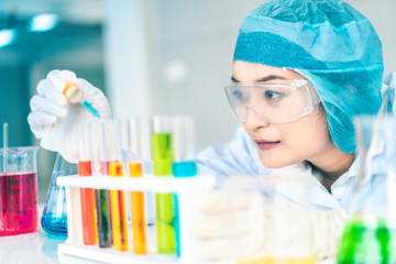 Asian Scientist Pipetting at a Biomedical Laboratory.Focused young life science professional pipetting solution into the glass cuvette. Lens focus