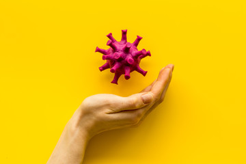 Corona virus Covid-19 - diagnostics concept with strain virus model and hands - on yellow background top-down