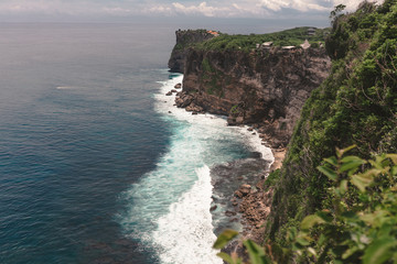 The beautiful nature of Indonesia and the island of Bali. Slopes and cliffs overlooking the waves of the blue ocean. Tropical and exotic view of travel to Asia
