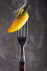 slice of fried potatoes with rosemary on a fork on a dark background