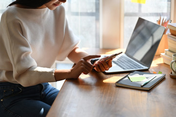 Cropped image of beautiful woman working as secretary holding/using a black blank screen smartphone...