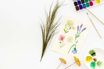 Drawing flowers with watercolor paintis on white background top-down frame copy space