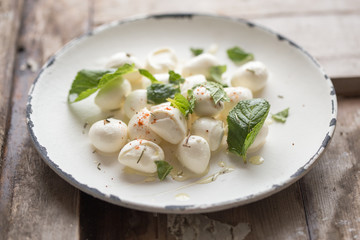 Mozzarella cheese balls in plate with mint . Traditional Italian food concept. Top view