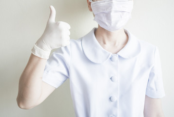 Woman nurse wearing mask raises the thumbs up to compliment people who work at home and social...