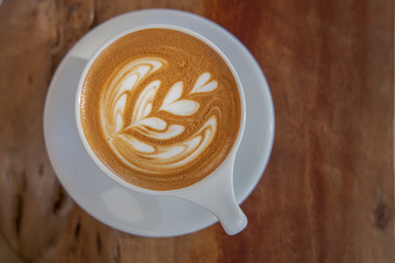 Close up of coffee cup with coffee latte art on a top. Latte art coffee over wooden background.
