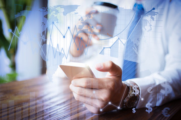 Businessman using modern device with financial analysis graphs. Unrecognizable entrepreneur solving business issues when he drinking coffee. He using mobile Internet. Technology concept