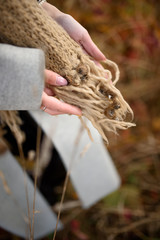 The girl holds in her hands a scarf full of burrs.