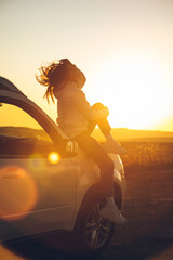 woman stop at roadside to enjoy sunset. sitting on car hood