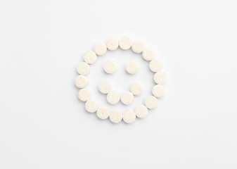 Happy face made of pills on white background