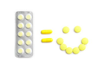 Blister pack and happy face made of pills on white background