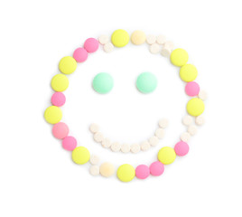 Happy face made of pills on white background