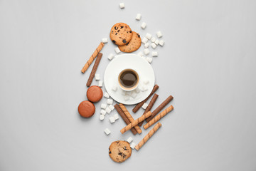 Sweets with cup of coffee on light background