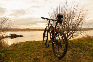 Obraz premium View of the lake and sky with sunset from behind a black sports mountain bike