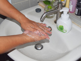 Washing hands with whipping foam in bathroom.