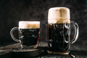 Dark beer in two mugs, horizontal, side view