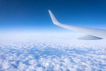 Airplane wing flying above the clouds, aerial view.
