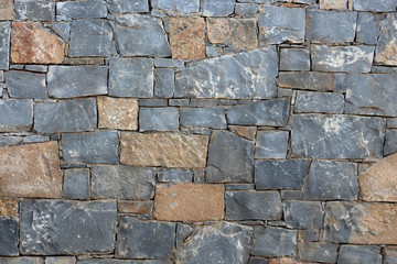 background of a solid gray stone wall of cement, limestone, sand and light multi-colored cobblestones with an uneven surface, of different sizes and shapes