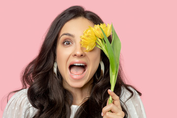 Young pretty dark-haired woman holding yellow flowers and looking excited
