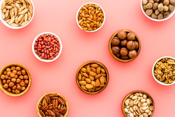 Set of macadamia, hazelnut, walnut, almond, pistachio, pecans nuts on pink background top-down pattern