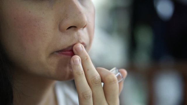Asian woman use finger applying lip gloss on her lip doing make up