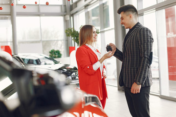 Couple in a car salon. Family buying the car. Elegant woman with her boyfriend.