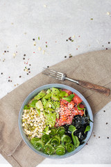 Salted salmon poke bowl with avocado, sea cale, cucumber, sesame seeds and bean sprouts on grey background