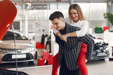 Couple in a car salon. Family buying the car. Elegant woman with her boyfriend.