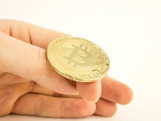 a man's hand is going to flip a gold coin bitcoin
