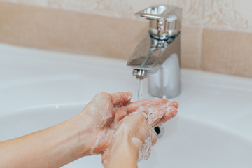 Woman use soap and washing hands under the water tap. Hygiene concept hand detail.