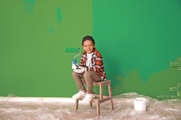 Little African-American painter near color wall