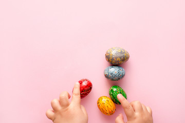 Close up of little girl holding colorful Easter eggs on pink background