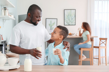 Fototapeta premium African-American boy and his father drinking milk in kitchen
