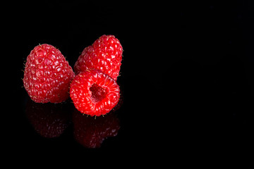Artistic fresh raspberries reflection on a black reflective surface. Raspberry with black background