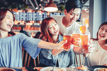 happy young group dining and drinking beer at restaurant