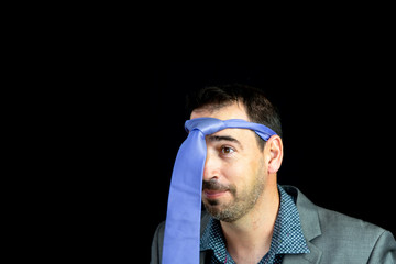 Obraz premium Bearded young man dressed in gray suit posing with tie on head after party night
