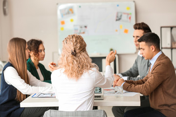 Female interior designer teaching young people in office