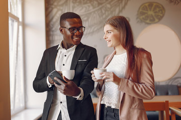 Black man in a cafe. International people. Man in a black suit. Woman in a pink jacket.