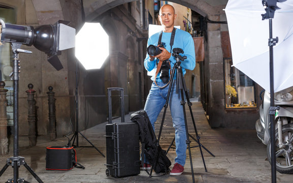 Photographer with camera among photo equipment