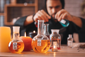 Flasks with potion and candles on table in alchemist's laboratory