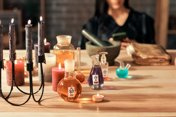 Bottles with potions and candles on table of alchemist - obrazy, fototapety, plakaty