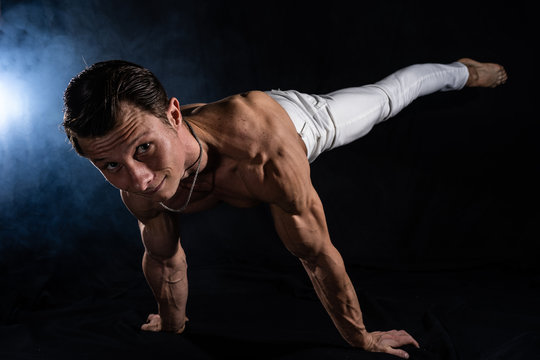 Muscular man making planche on black black background