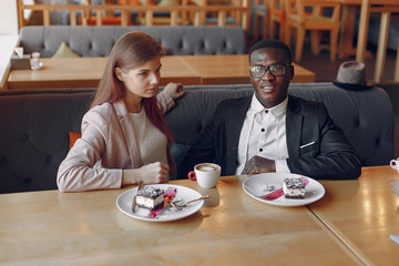 Black man in a cafe. International people. Man in a black suit. Woman in a pink jacket.
