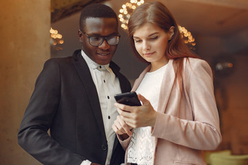 Black man in a cafe. International people. Man in a black suit. Woman in a pink jacket.