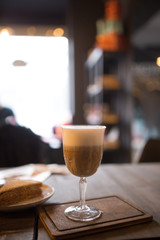 Cappuccino and a slice of cake on a table in a cafe.